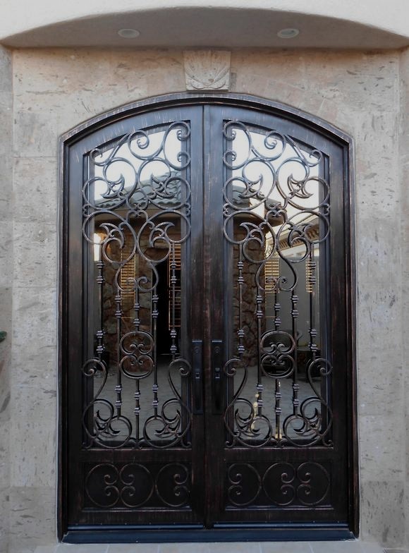 Ornate iron scrollwork double door in travertine surround
